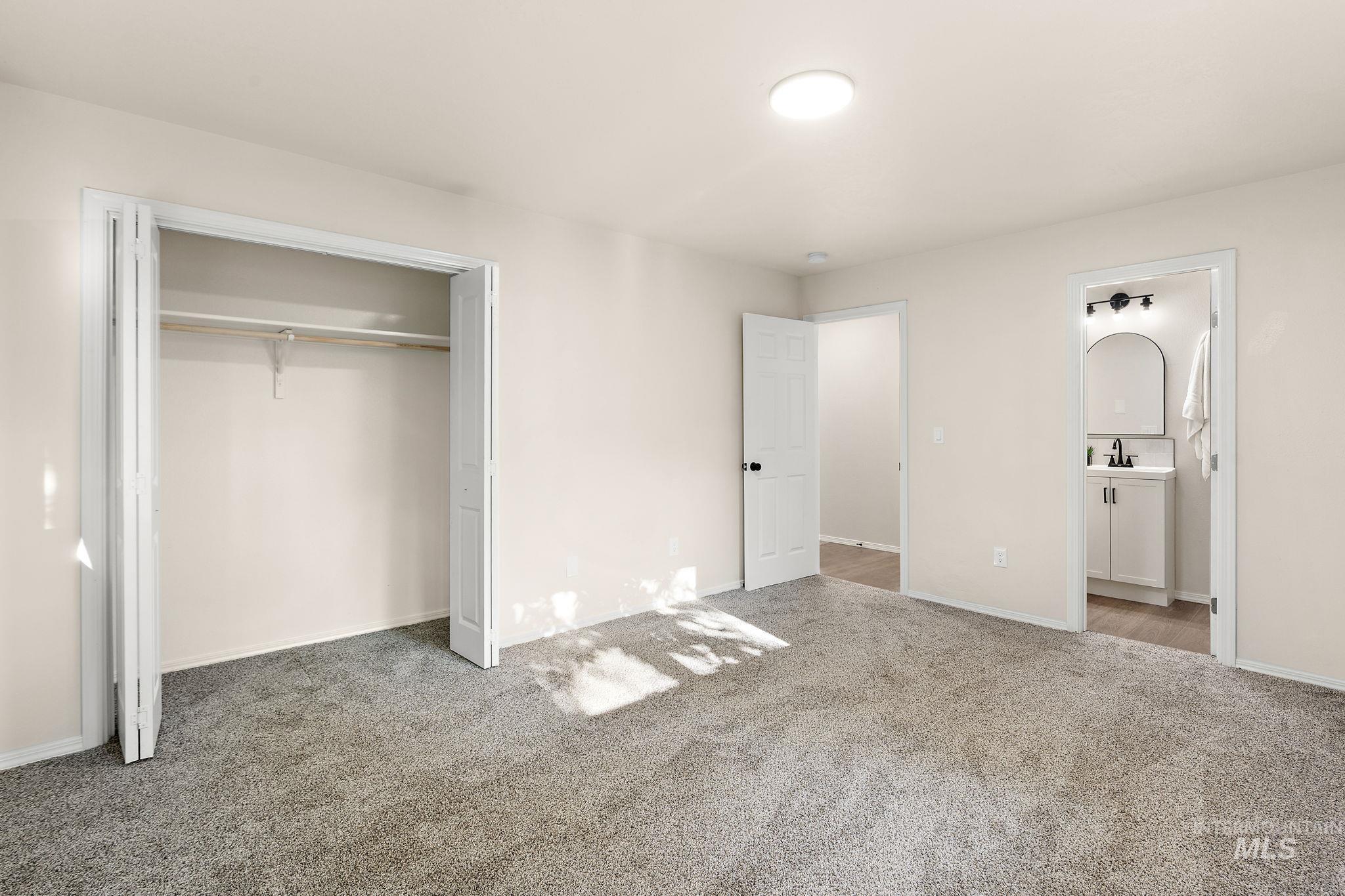 Unfurnished bedroom with carpet floors, a closet, and ensuite bath