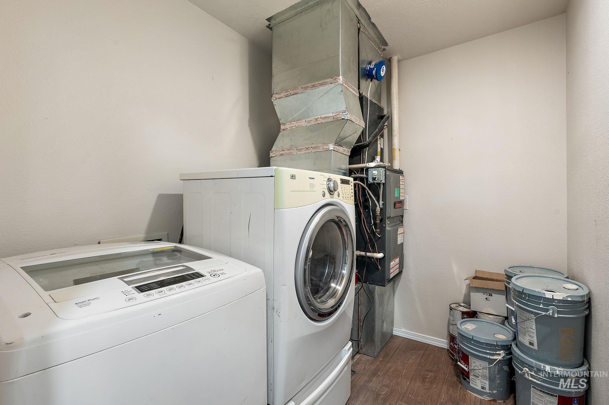 Laundry room featuring dark wood finished floors, washer and clothes dryer, and heating unit