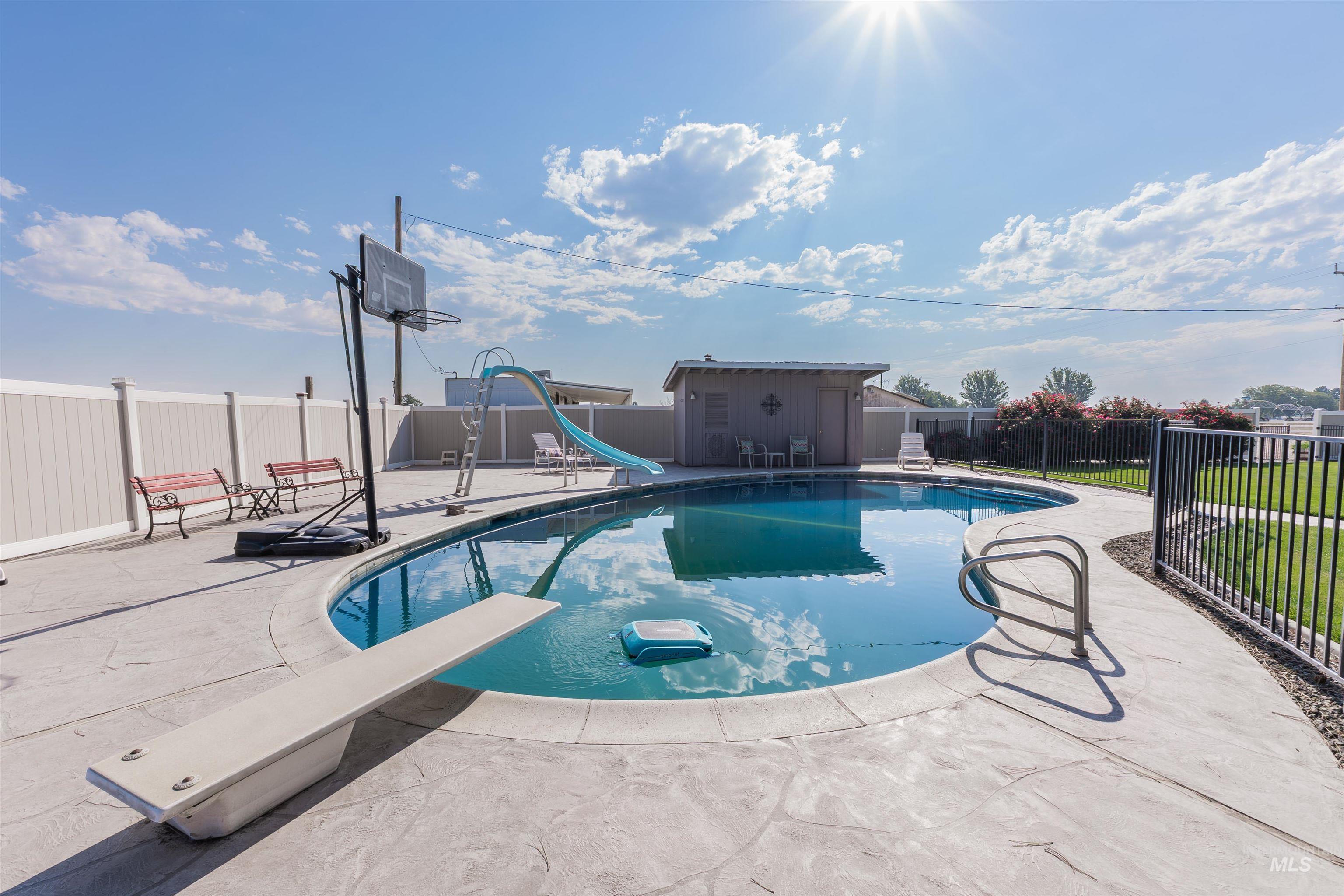 View of swimming pool with a water slide, a patio, a diving board, a fenced backyard, and an outdoor structure
