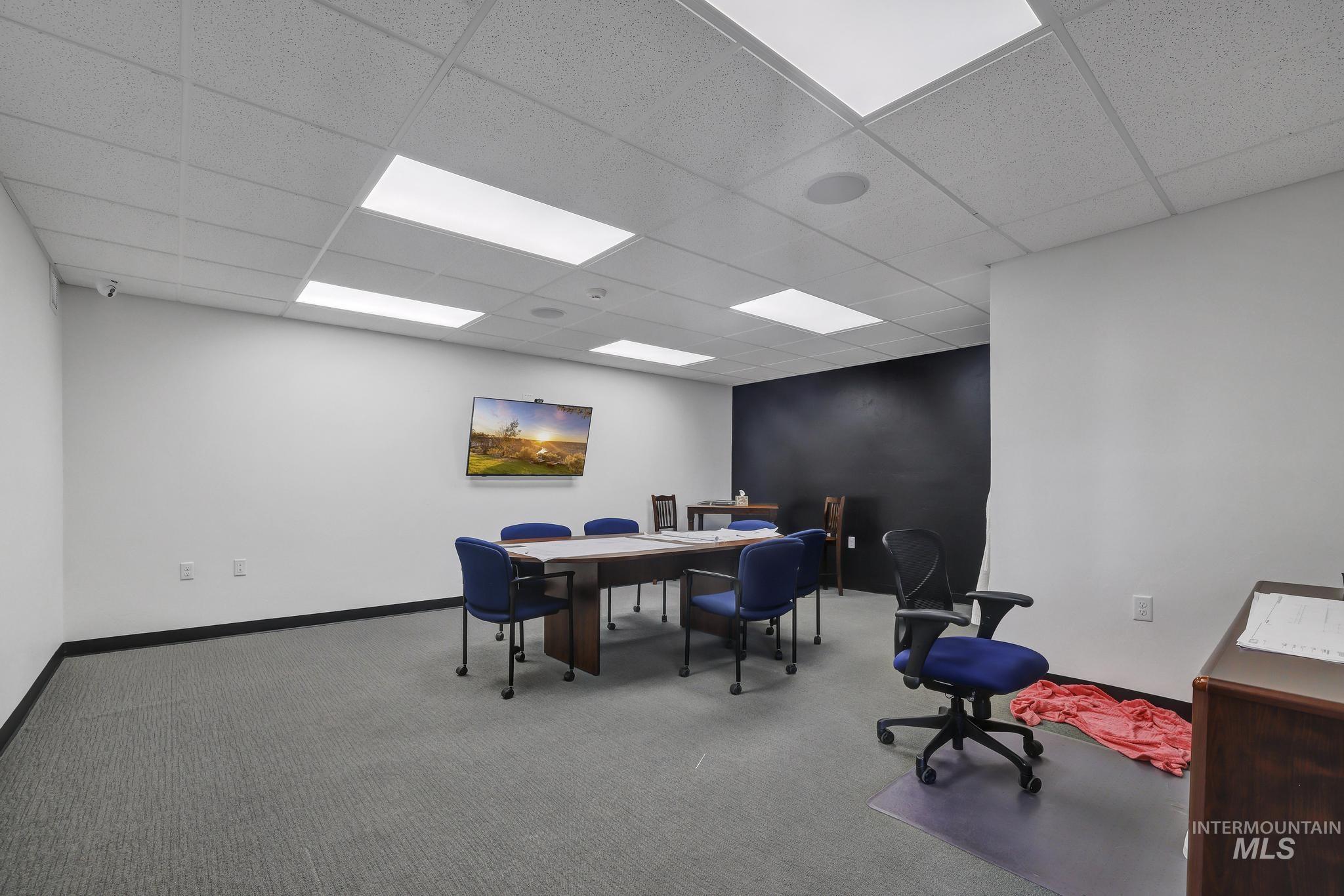 Carpeted office featuring a paneled ceiling and baseboards