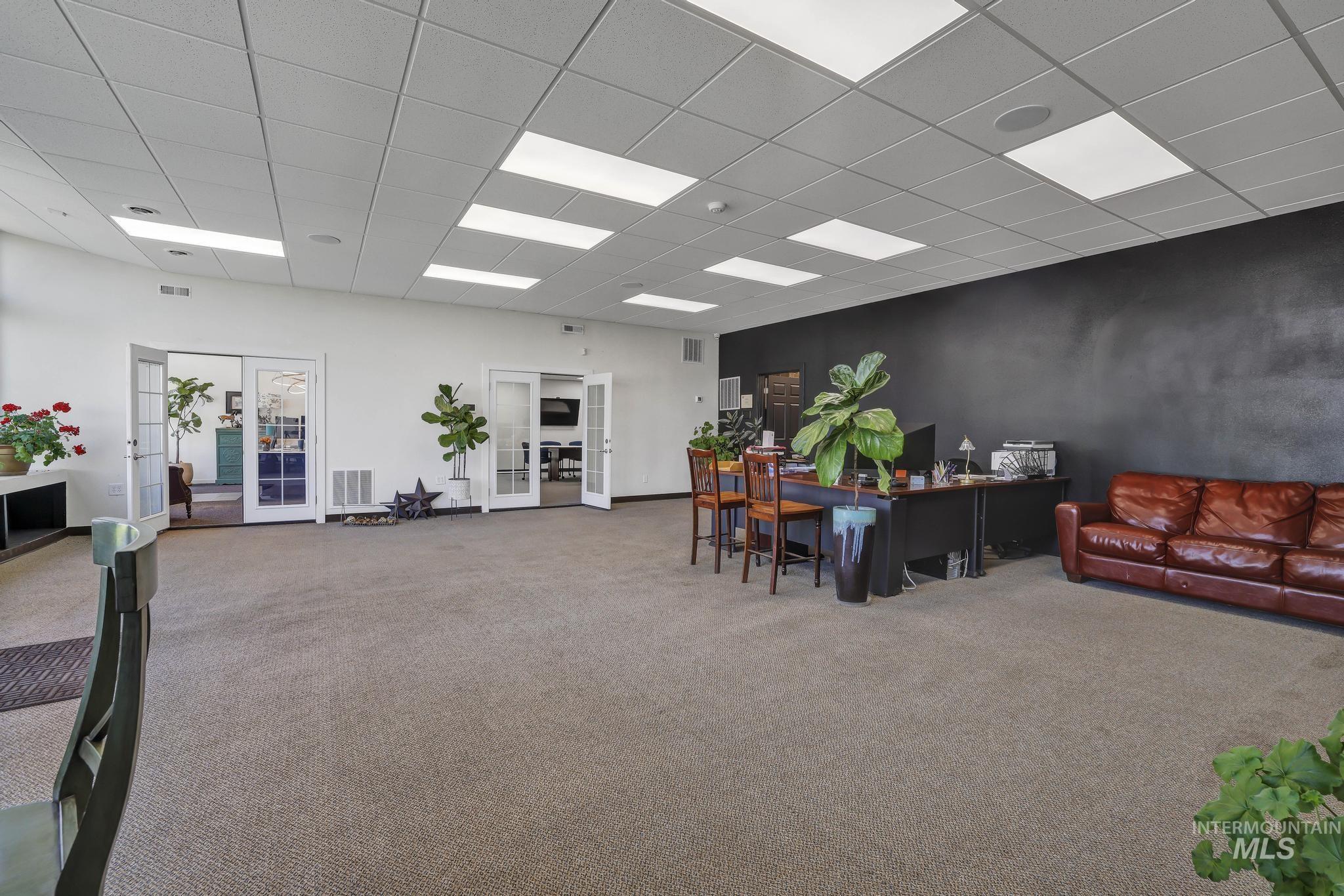 Interior space with french doors, a desk, and a drop ceiling