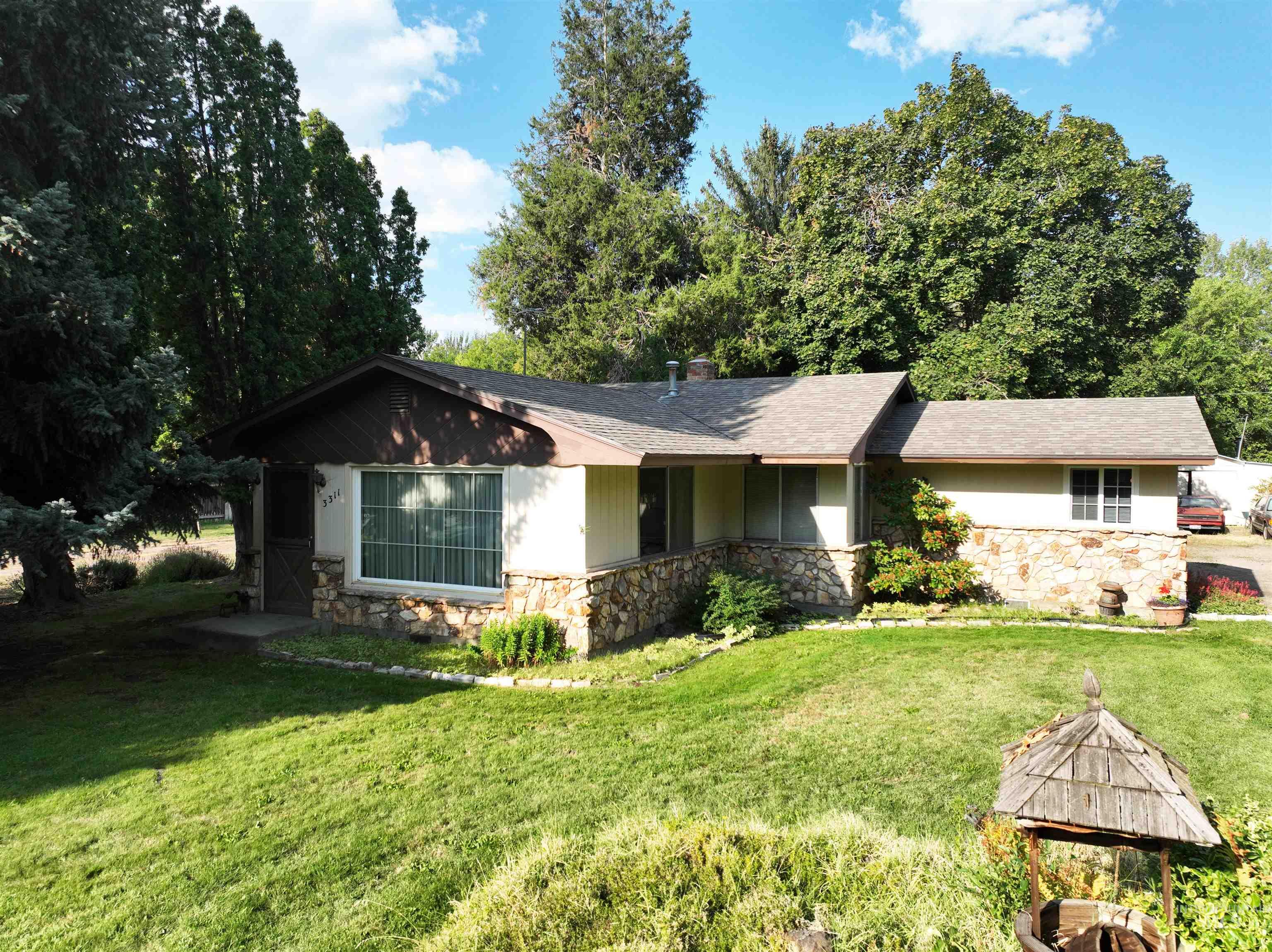 Ranch-style home with stone siding, a front lawn, and roof with shingles