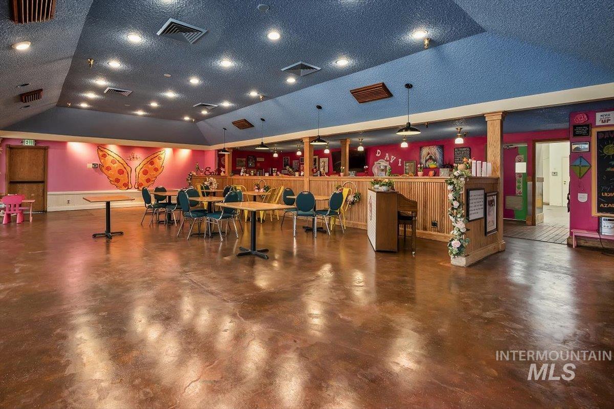 Miscellaneous room with finished concrete flooring, lofted ceiling, a textured ceiling, and a community bar