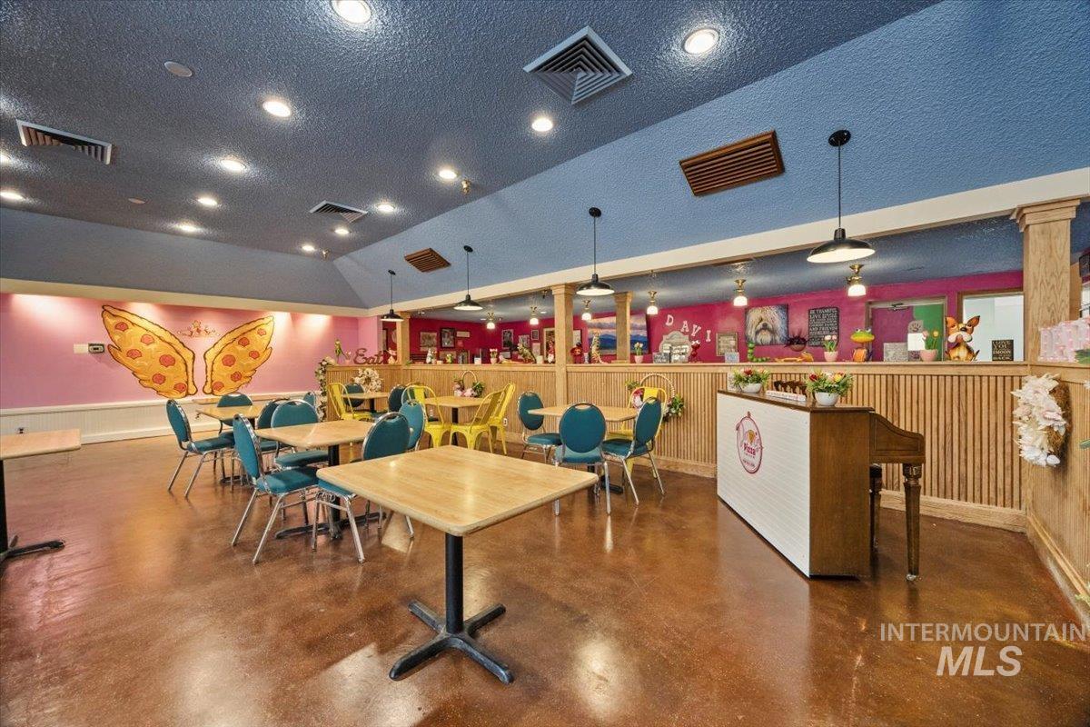 Game room featuring finished concrete flooring, a textured ceiling, lofted ceiling, and recessed lighting