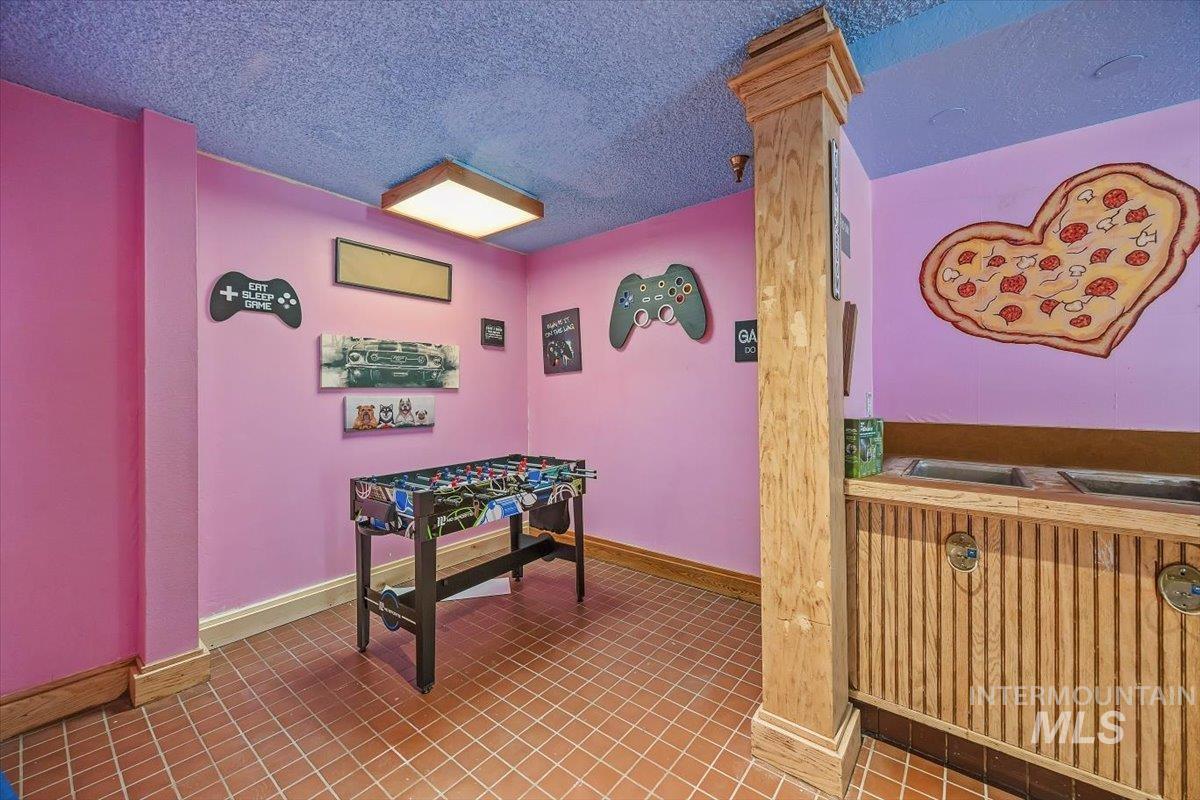 Recreation room with a textured ceiling and tile patterned flooring