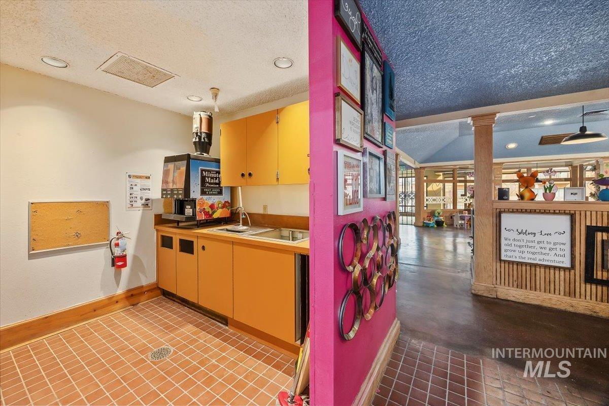 Kitchen featuring a textured ceiling, recessed lighting, decorative columns, light countertops, and red cabinetry