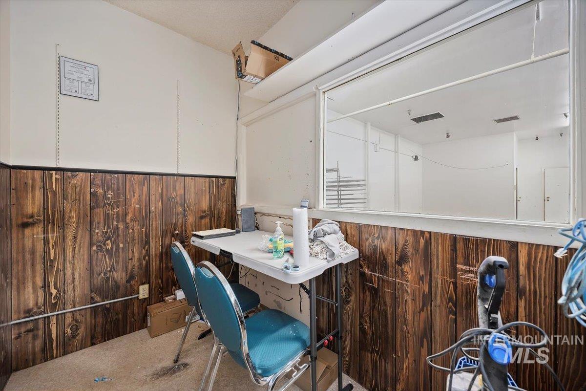 Carpeted dining space featuring wooden walls and wainscoting