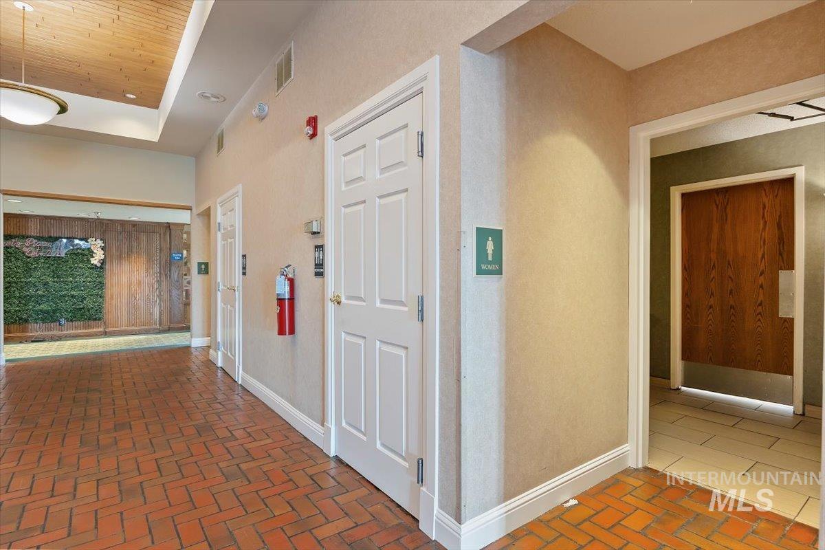 Hallway featuring brick flooring and baseboards