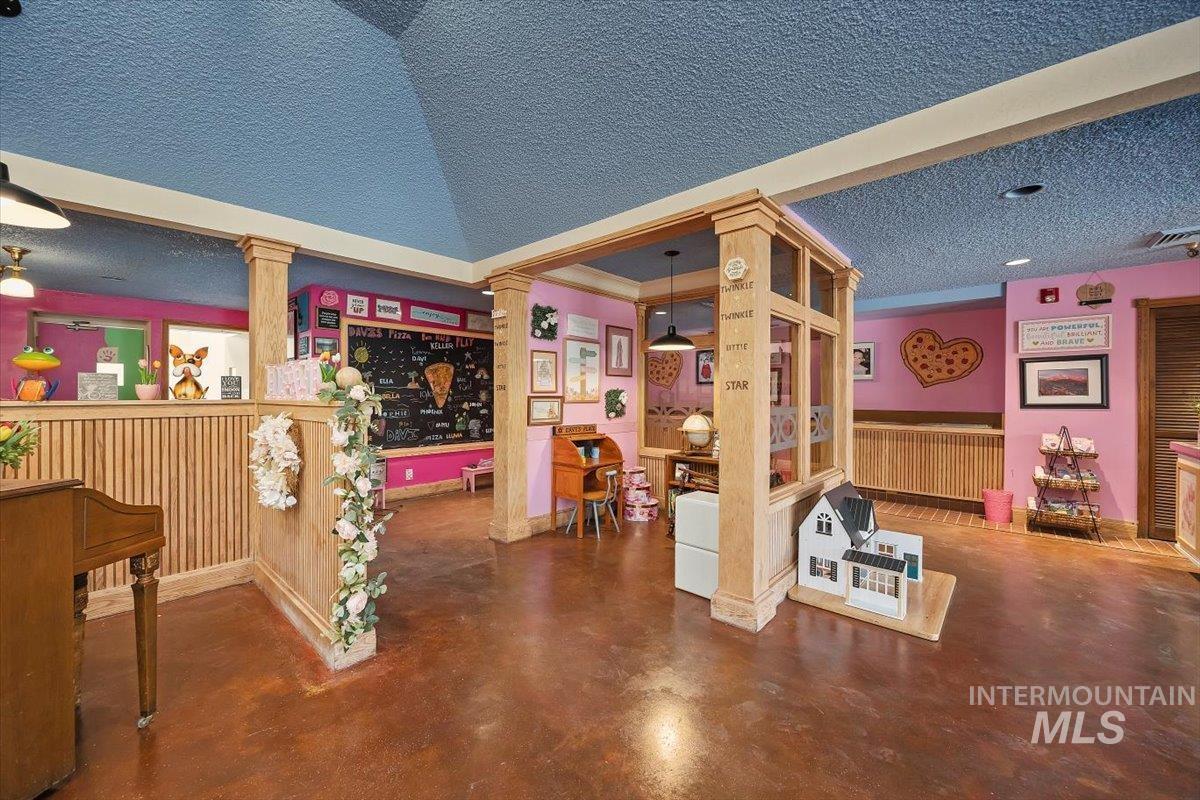Interior space with decorative columns, a textured ceiling, and finished concrete flooring