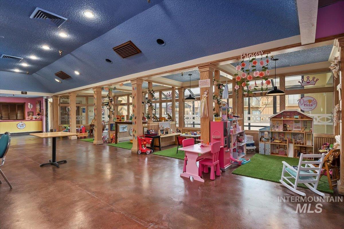 Game room with concrete flooring, lofted ceiling, a textured ceiling, and decorative columns