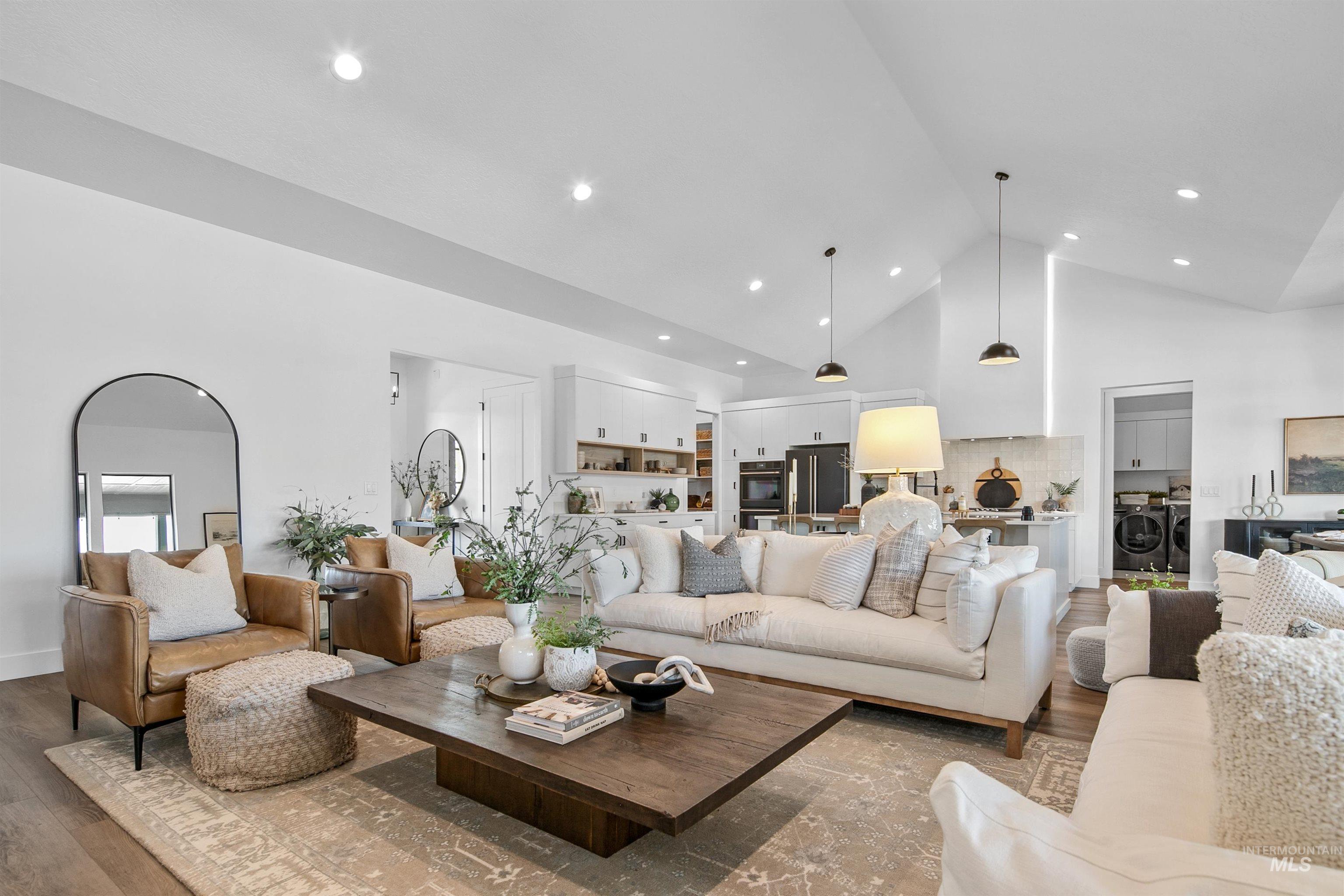 Living area with high vaulted ceiling, wood finished floors, and recessed lighting