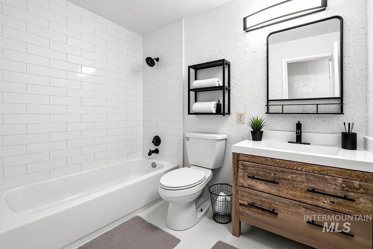 Full bathroom featuring a textured wall, shower / tub combination, and vanity