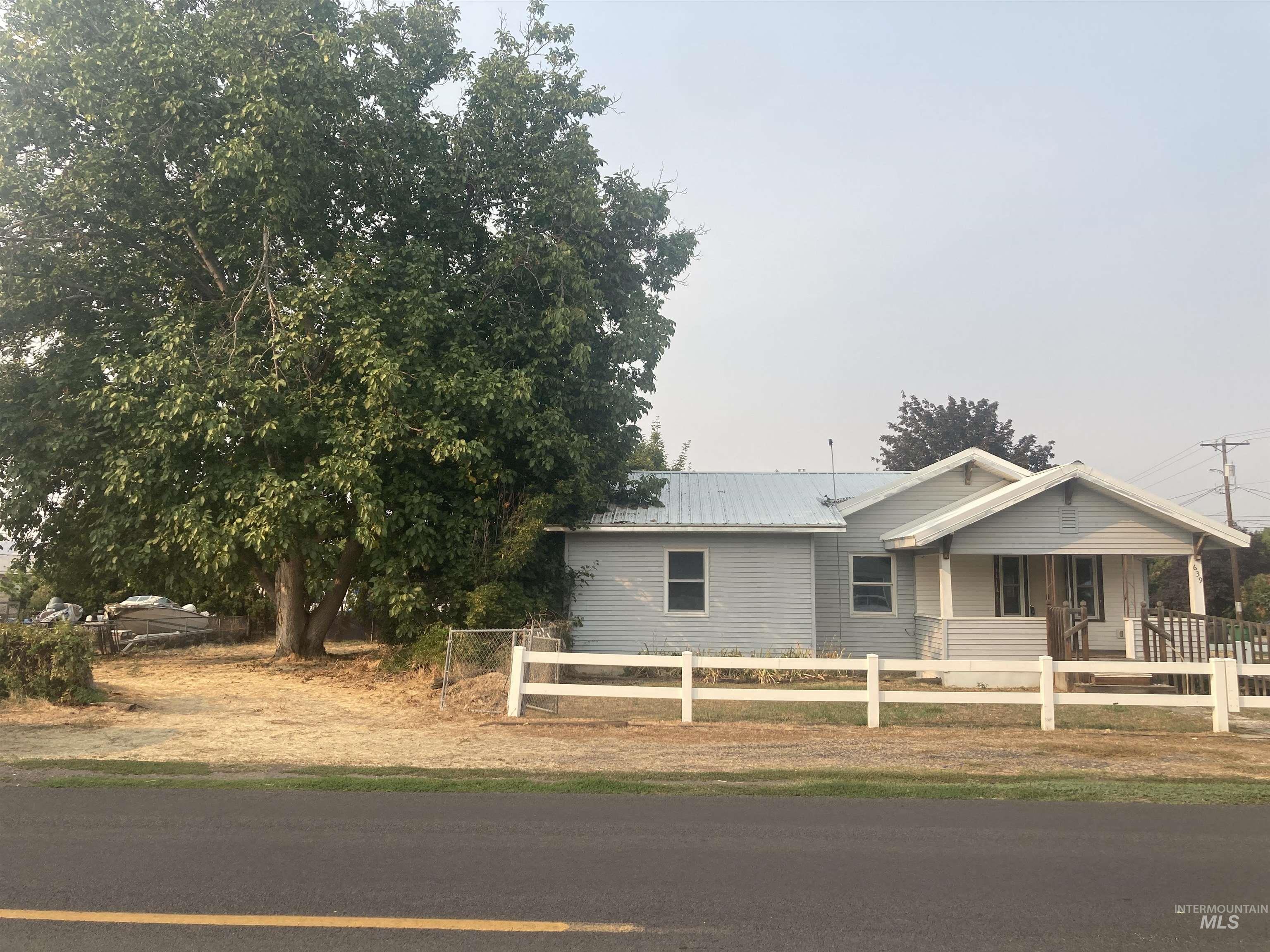 View of front facade featuring covered porch, a fenced front yard, and a metal roof