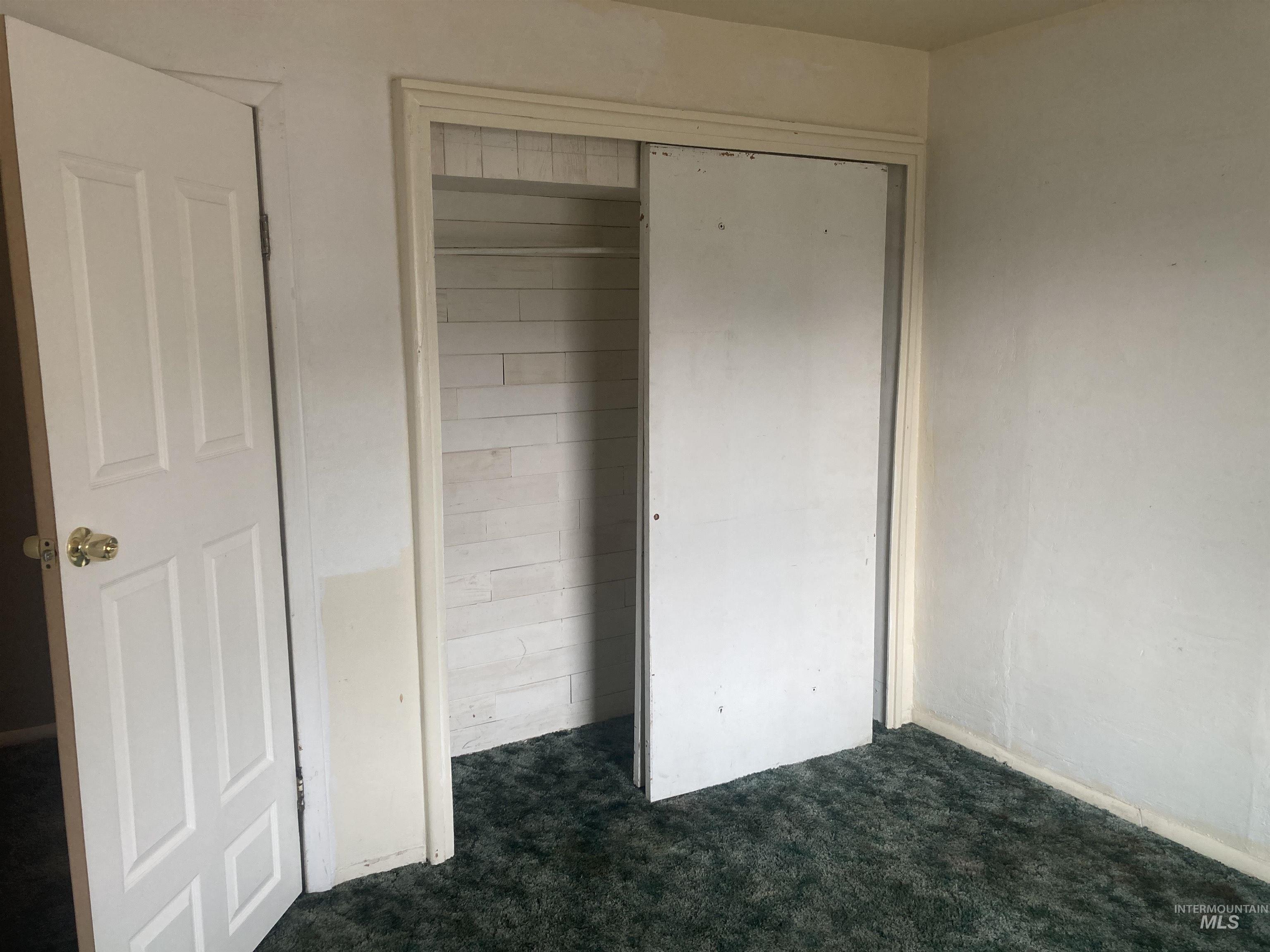 Unfurnished bedroom featuring dark carpet and a closet
