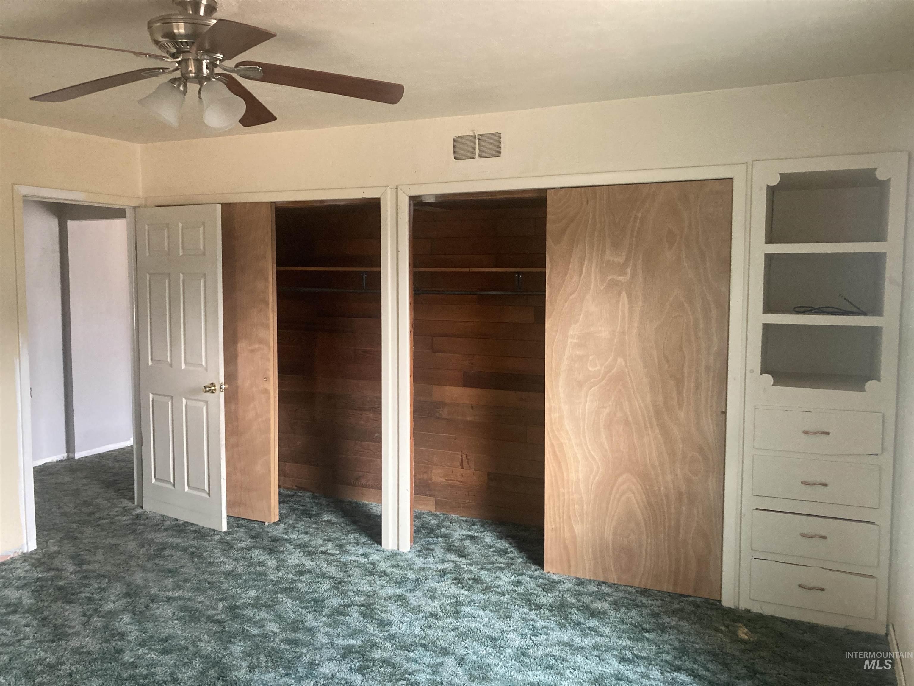 Unfurnished bedroom featuring multiple closets, dark colored carpet, and ceiling fan