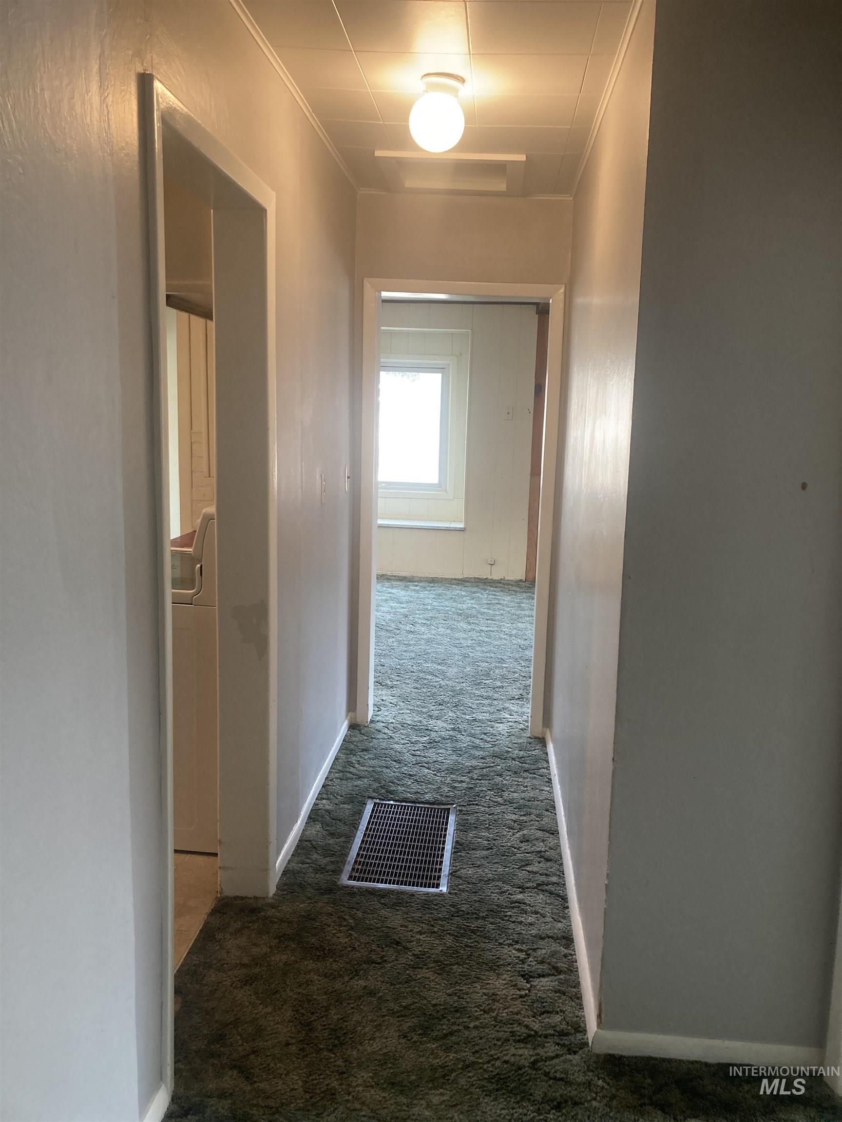 Hallway featuring dark carpet and crown molding