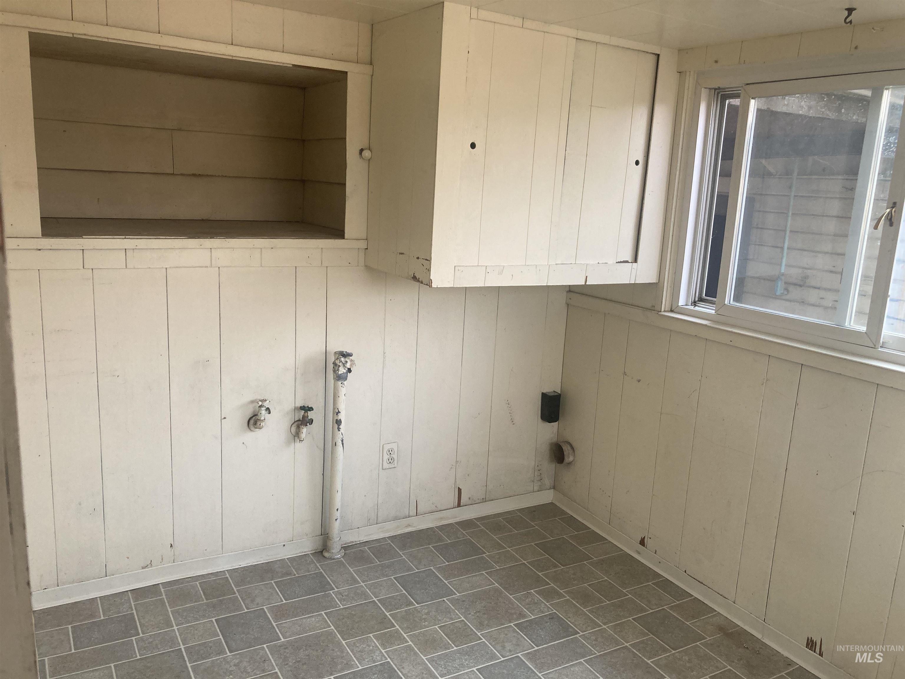 Laundry room featuring wood walls and baseboards