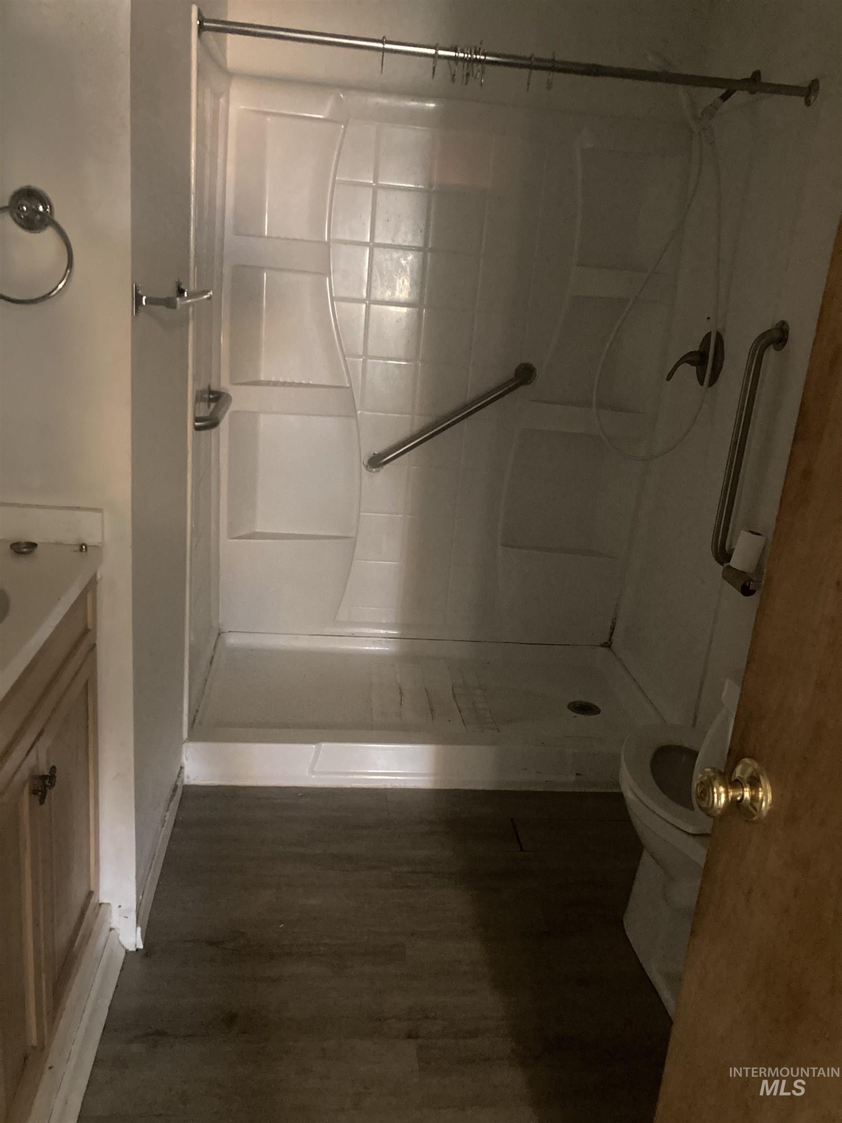 Full bathroom with a shower stall, vanity, and dark wood finished floors