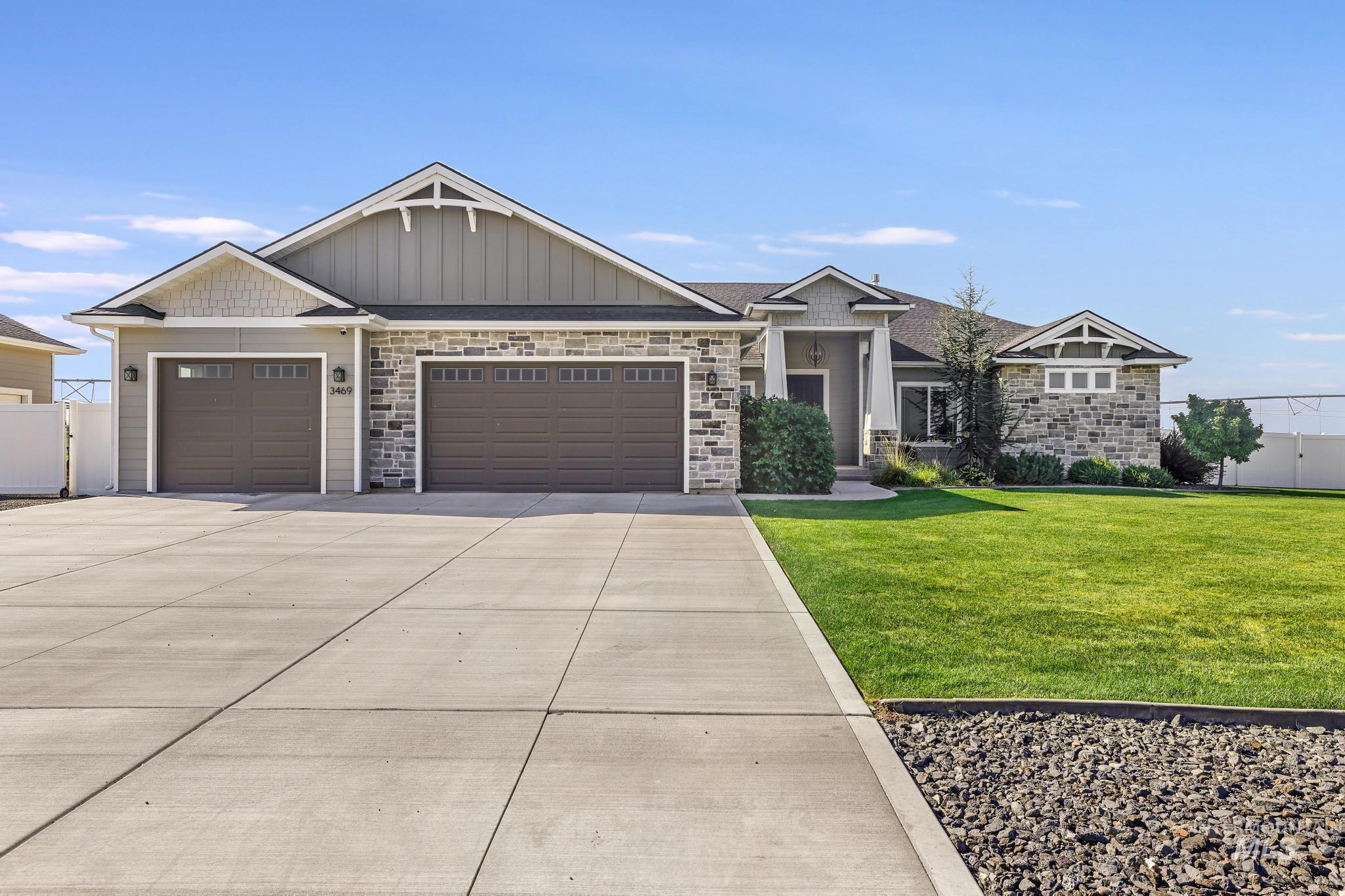 Craftsman house featuring a front yard, an attached garage, stone siding, concrete driveway, and board and batten siding