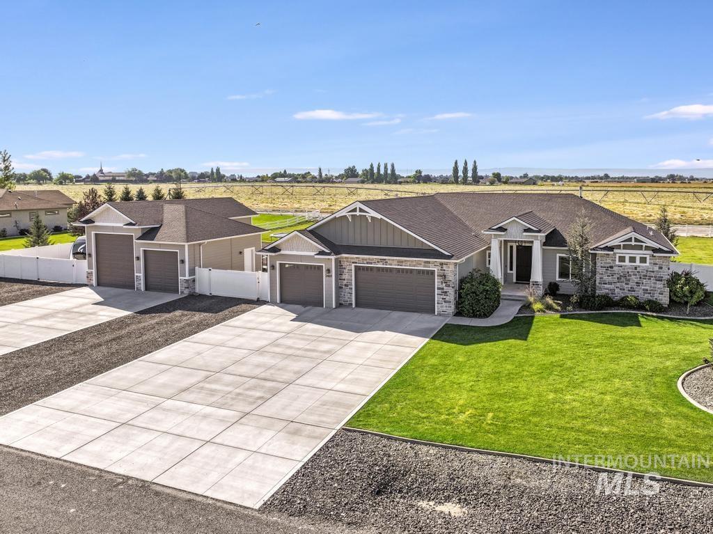 View of front facade featuring a view of countryside, a garage, concrete driveway, and stone siding