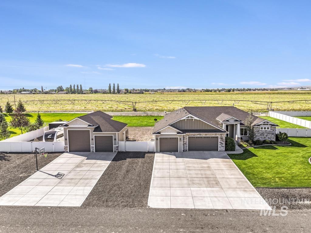 View of front of home with a rural view, a garage, stone siding, and concrete driveway