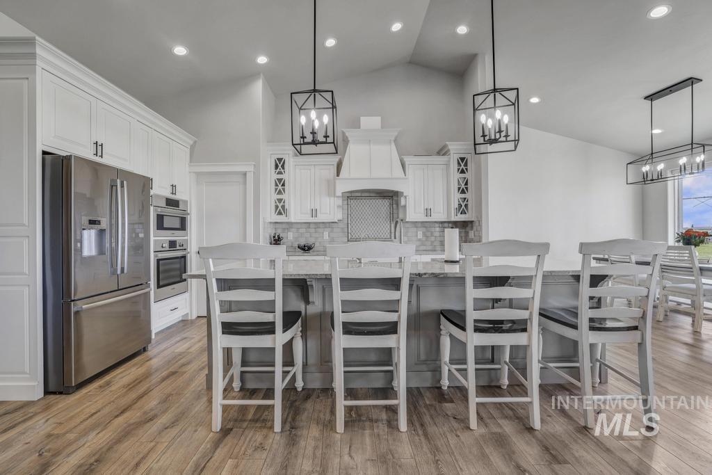 Kitchen with stainless steel appliances, white cabinetry, tasteful backsplash, decorative light fixtures, and recessed lighting
