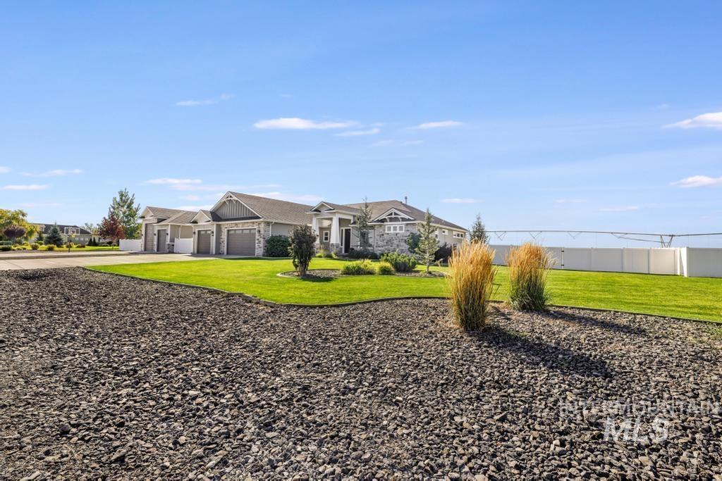 View of grassy yard with an attached garage and decorative driveway