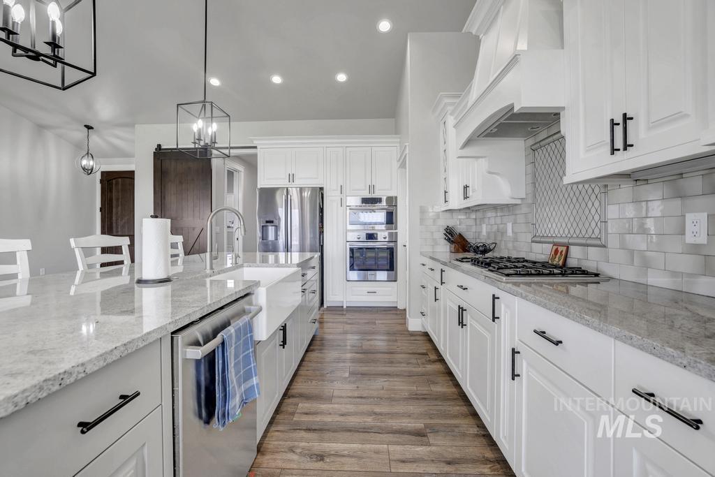 Kitchen with white cabinets, light stone counters, tasteful backsplash, appliances with stainless steel finishes, and recessed lighting
