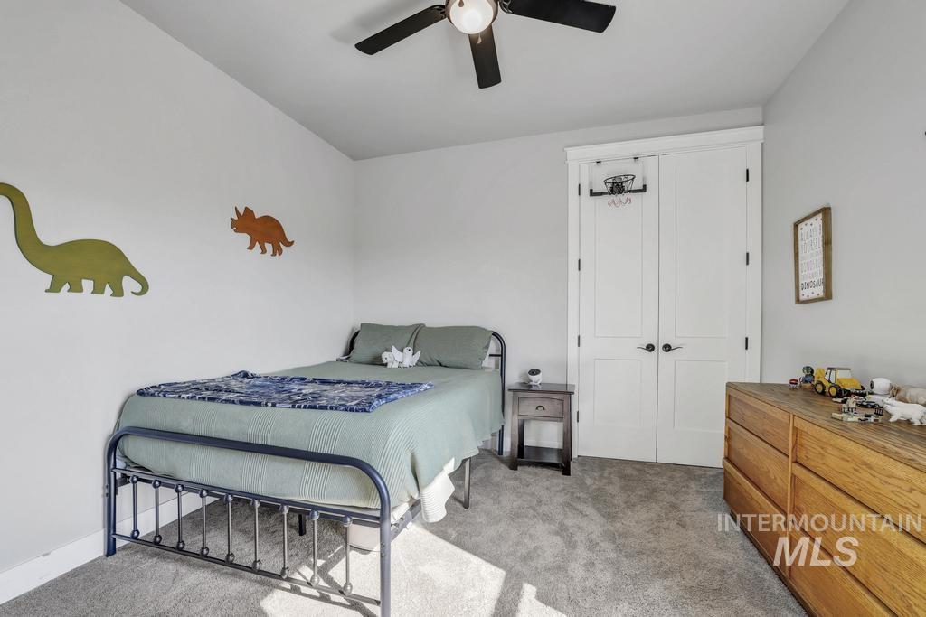 Bedroom with light colored carpet and a ceiling fan