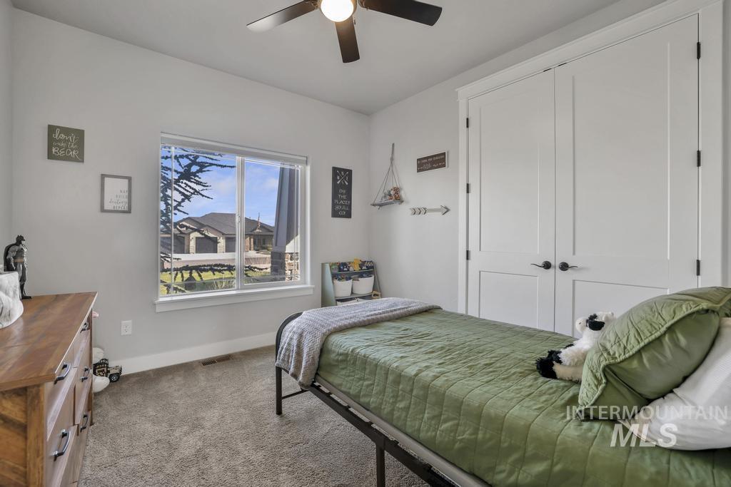 Carpeted bedroom featuring ceiling fan and a closet
