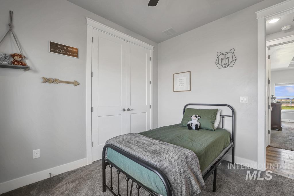 Carpeted bedroom featuring ceiling fan and a closet