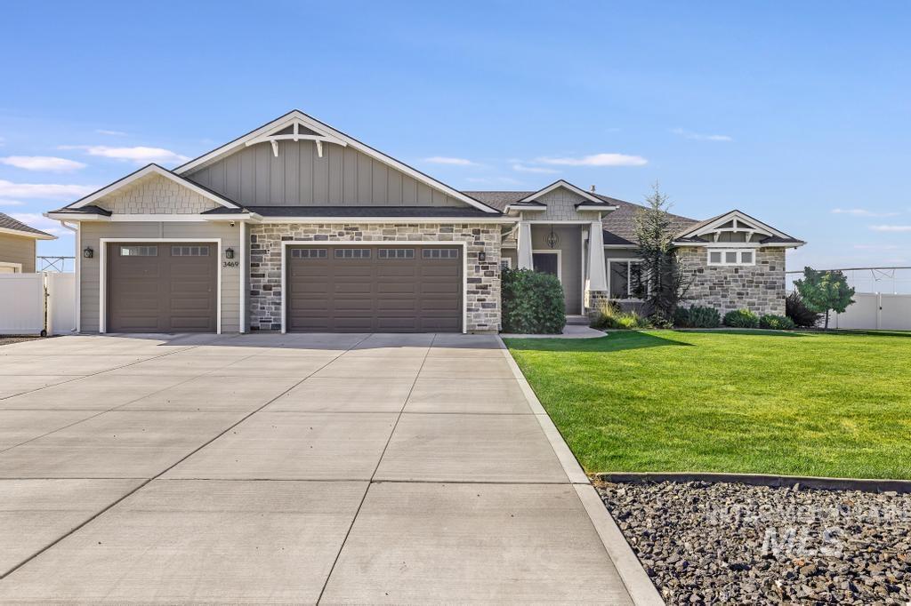 Craftsman inspired home with a front yard, an attached garage, driveway, stone siding, and board and batten siding
