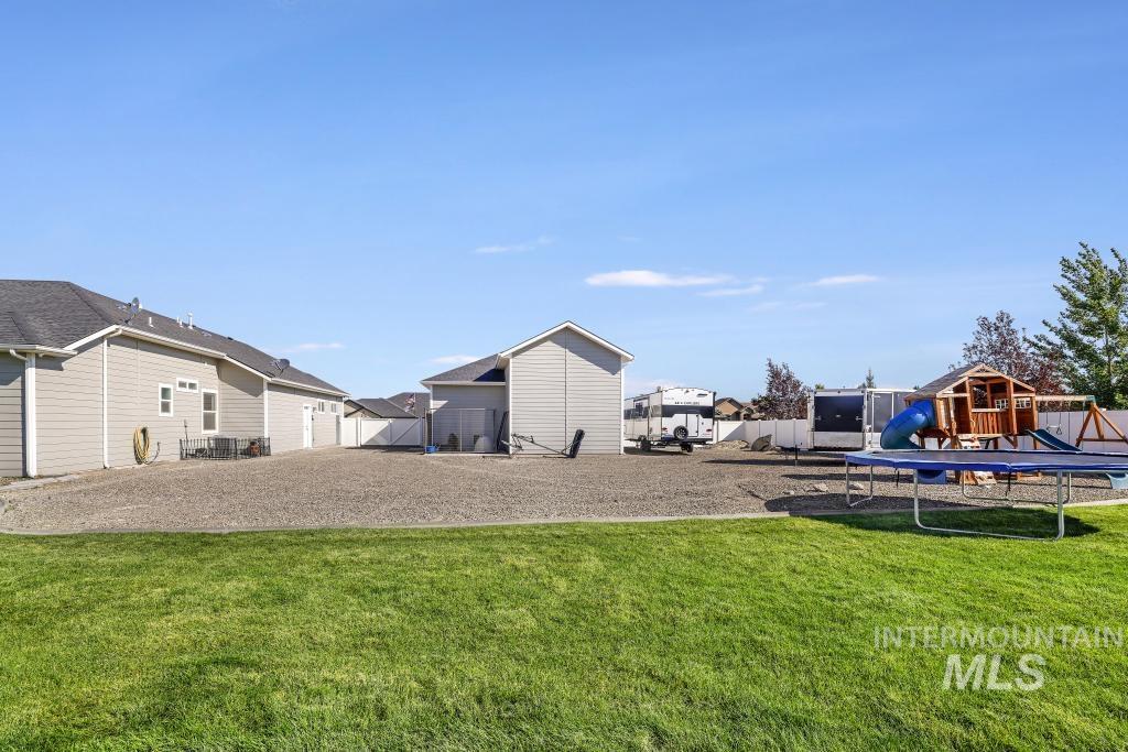 View of yard with a playground and a trampoline