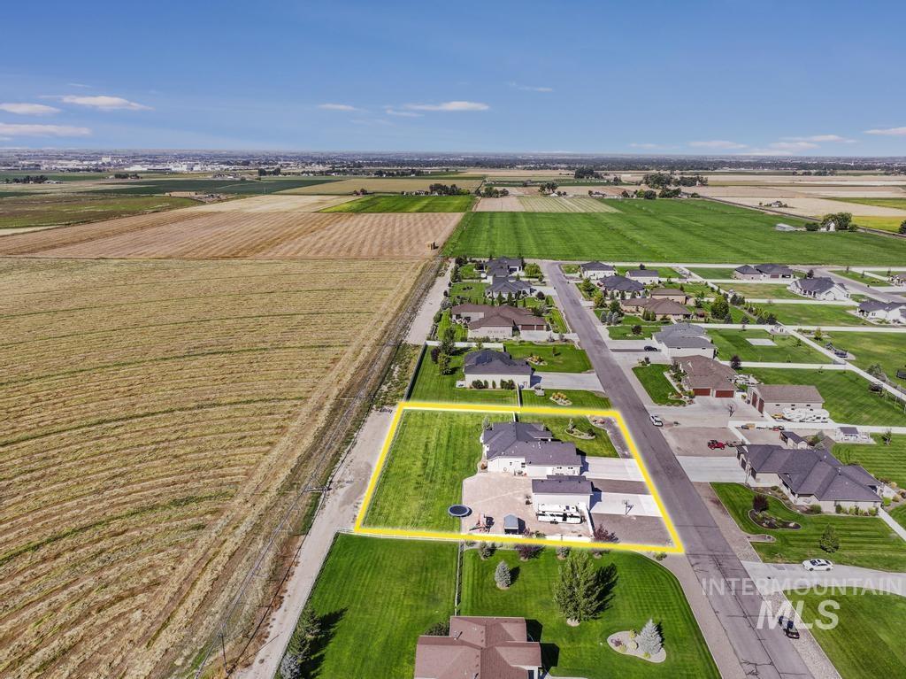 Aerial view of sparsely populated area with property parcel outlined, farmland, and nearby suburban area