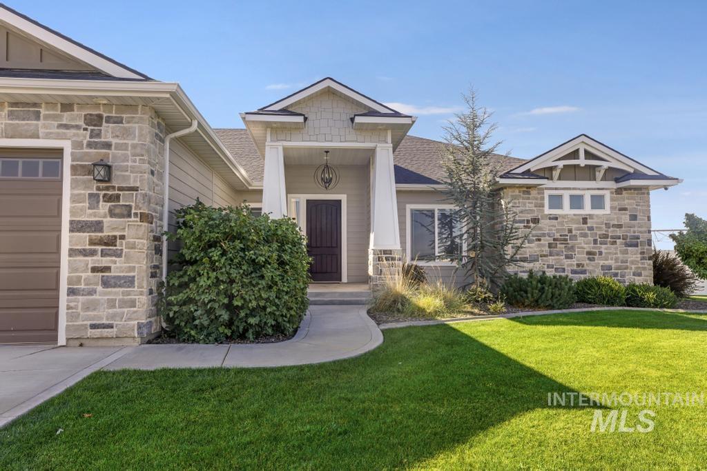 Entrance to property with stone siding, a lawn, and covered porch