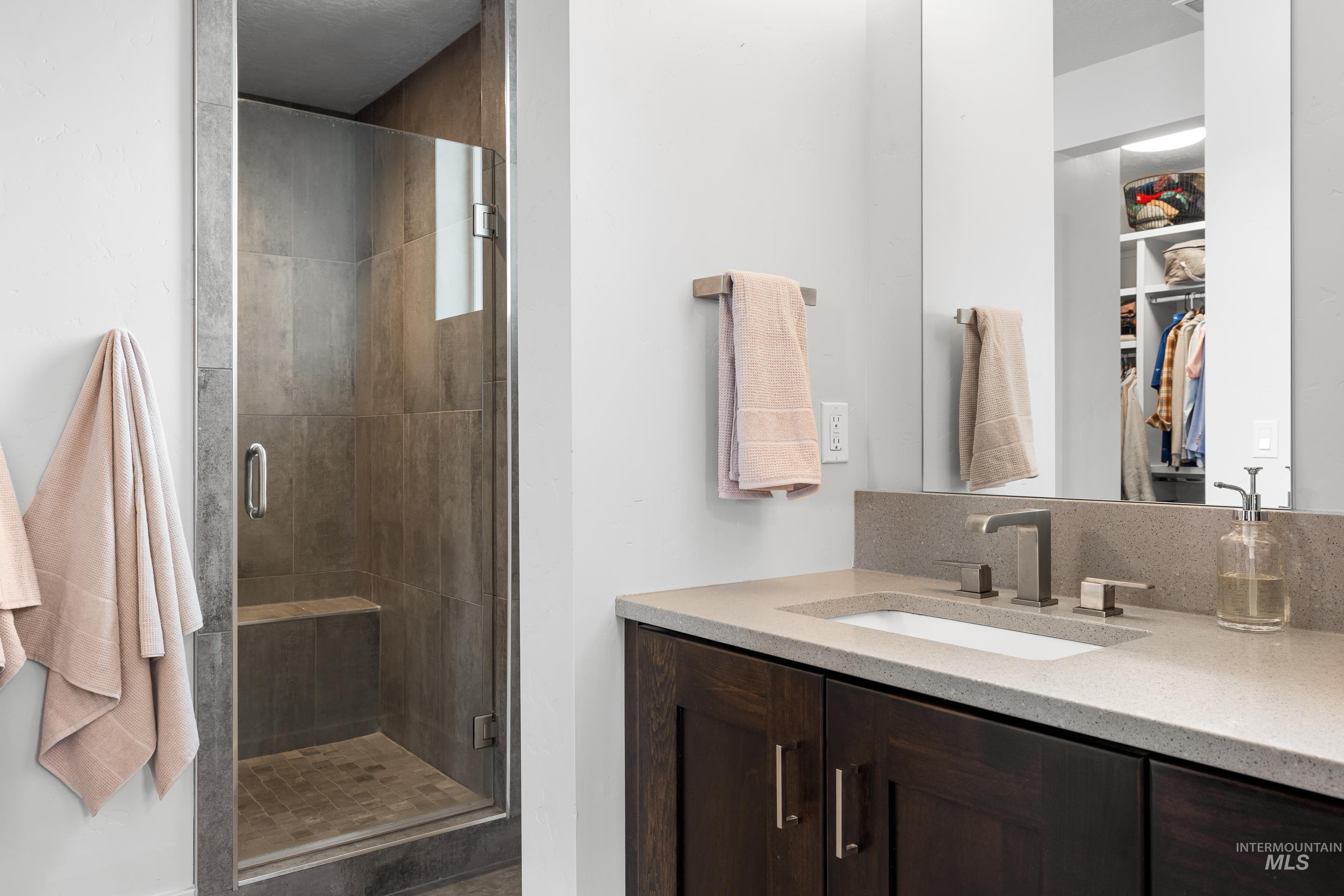 Bathroom featuring a stall shower, a walk in closet, and vanity