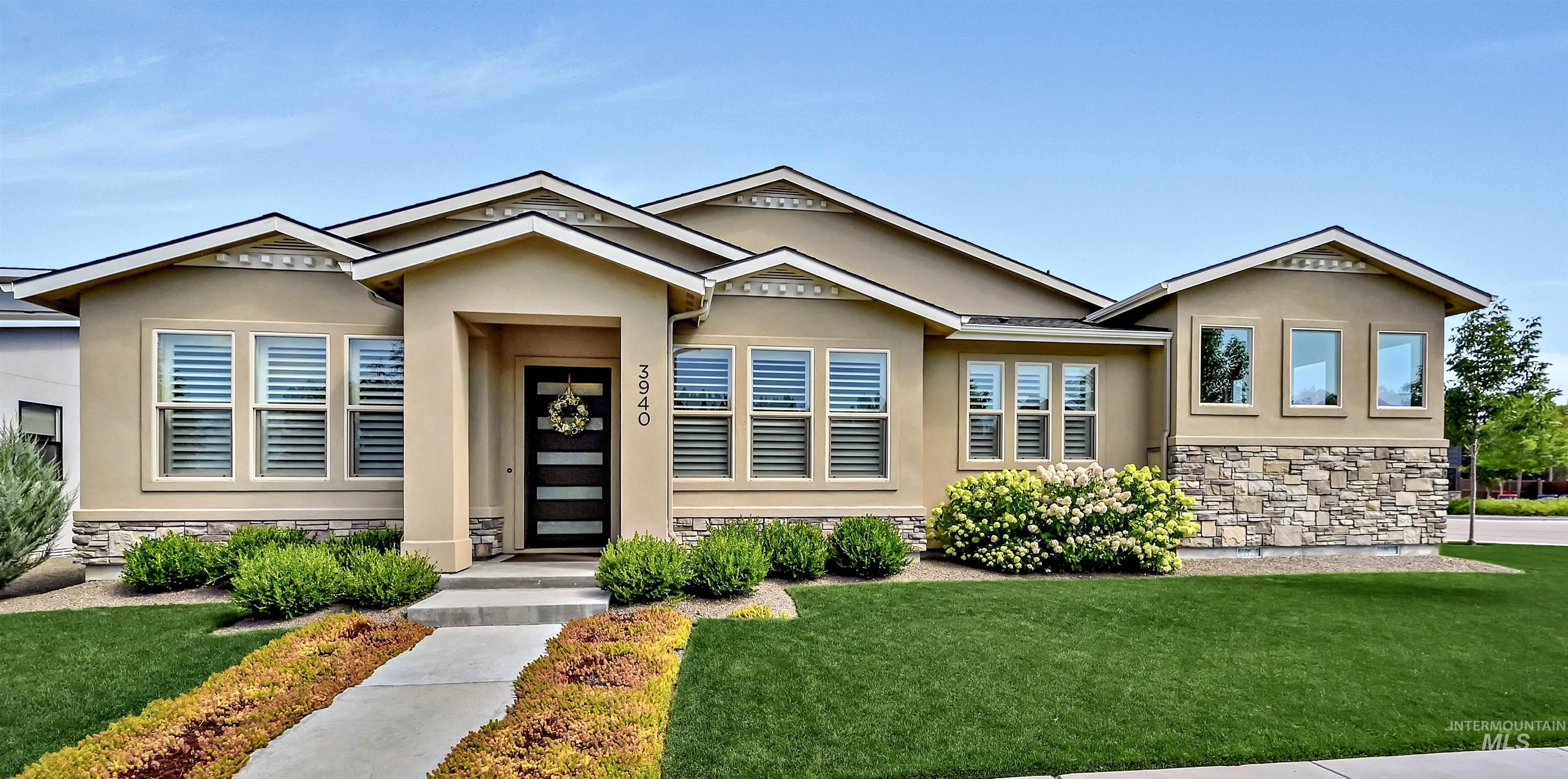 View of front of home featuring stone siding, a front yard, and stucco siding