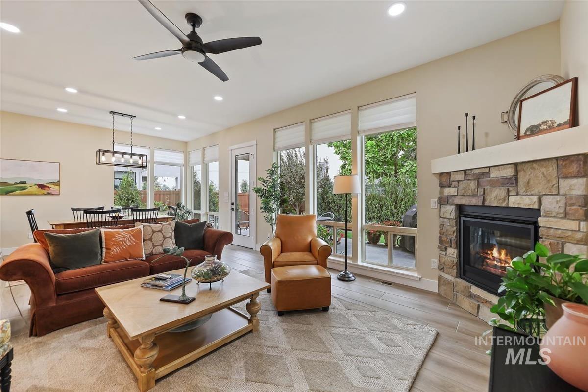 Living room featuring light wood-type flooring, recessed lighting, ceiling fan, and a fireplace