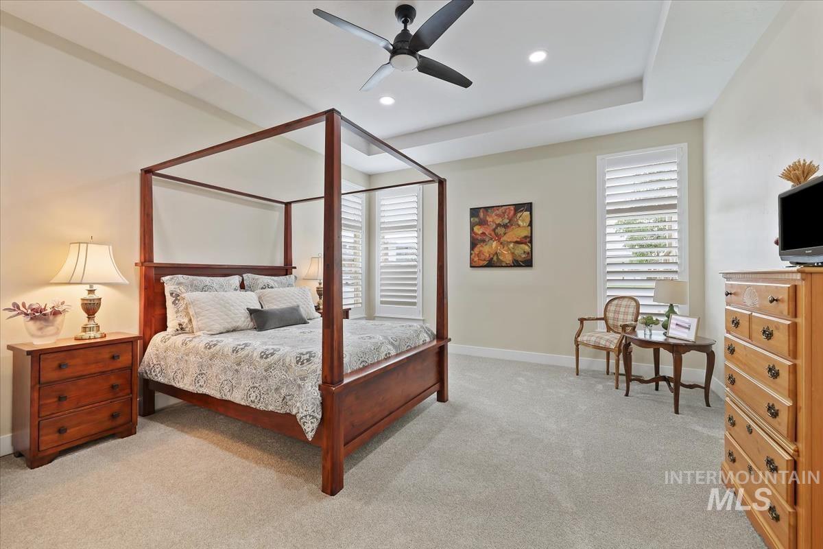 Bedroom with light carpet, a ceiling fan, recessed lighting, and a tray ceiling