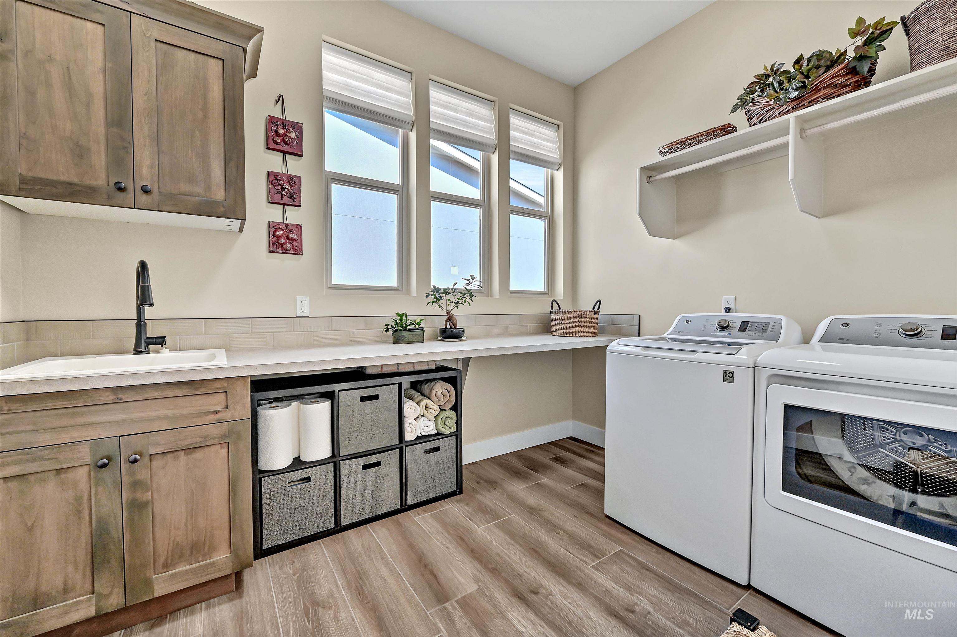 Laundry area with washing machine and dryer, cabinet space, and light wood finished floors