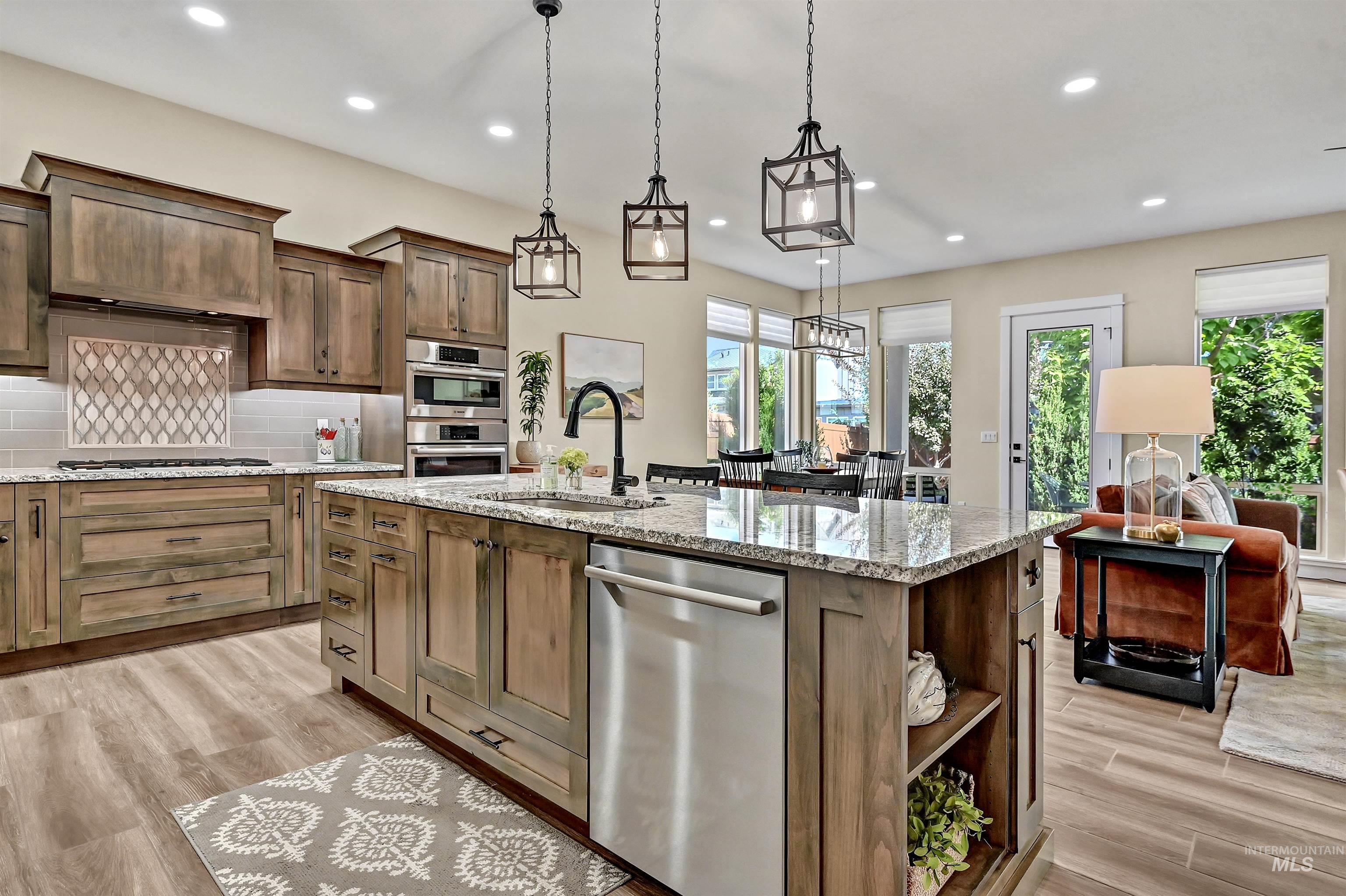 Kitchen with appliances with stainless steel finishes, backsplash, light wood-type flooring, recessed lighting, and decorative light fixtures