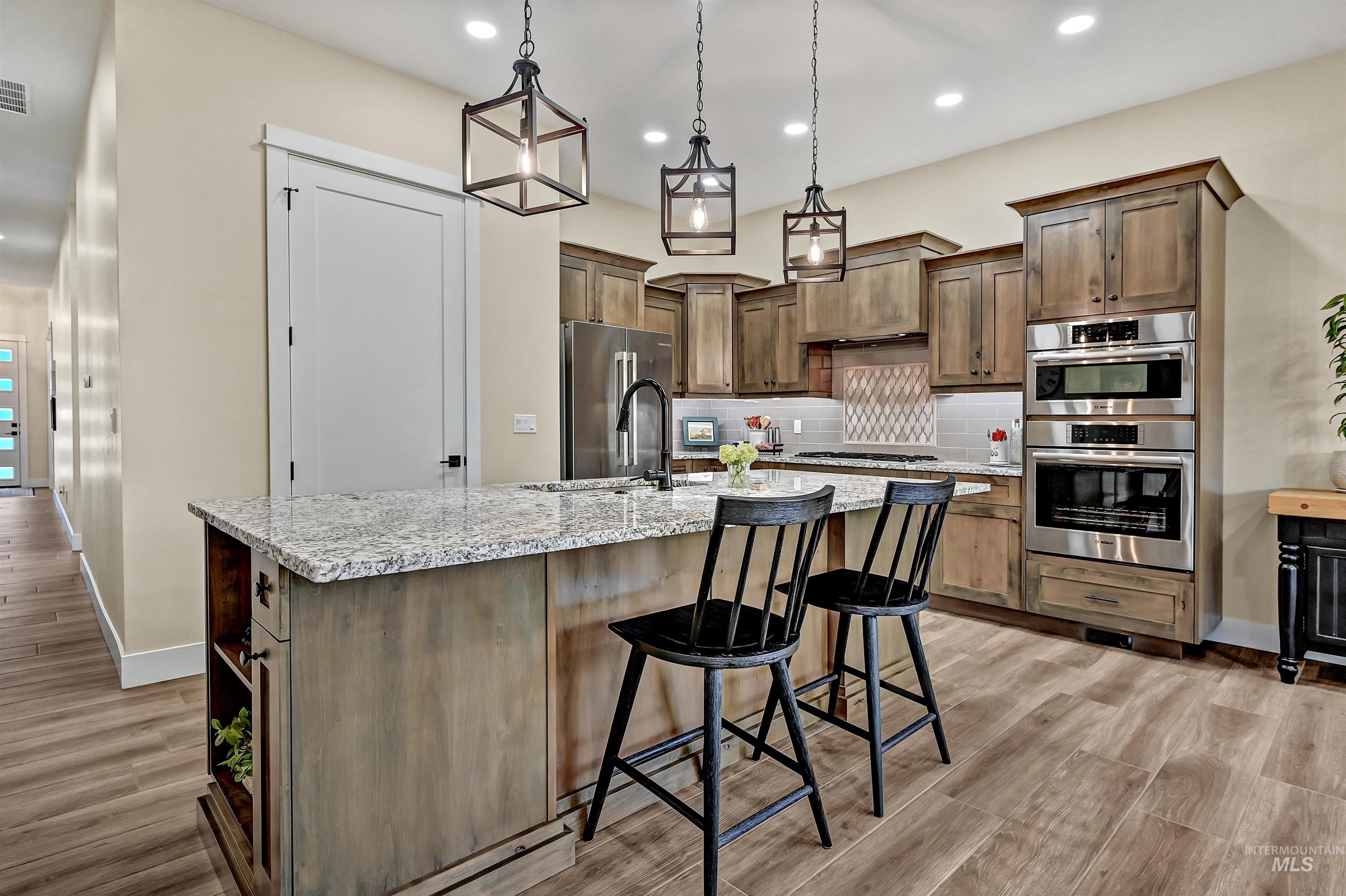 Kitchen featuring backsplash, light wood-type flooring, an island with sink, a breakfast bar area, and recessed lighting
