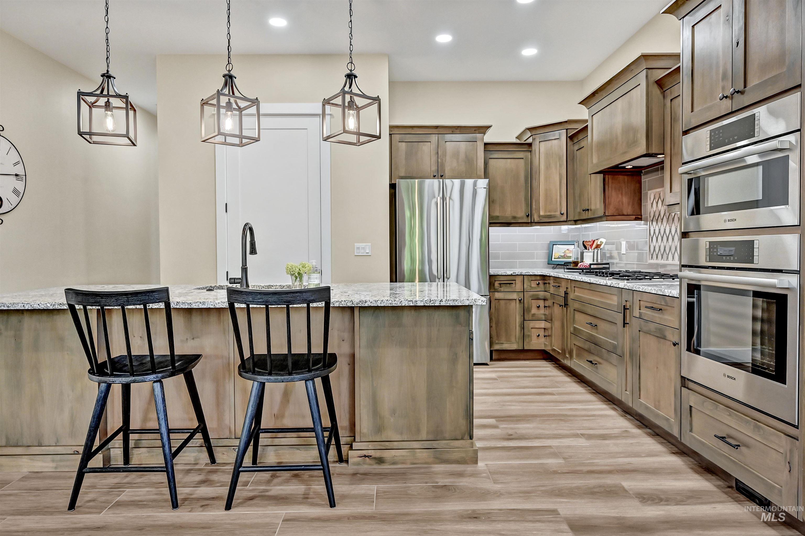 Kitchen with appliances with stainless steel finishes, tasteful backsplash, recessed lighting, a breakfast bar area, and light stone countertops