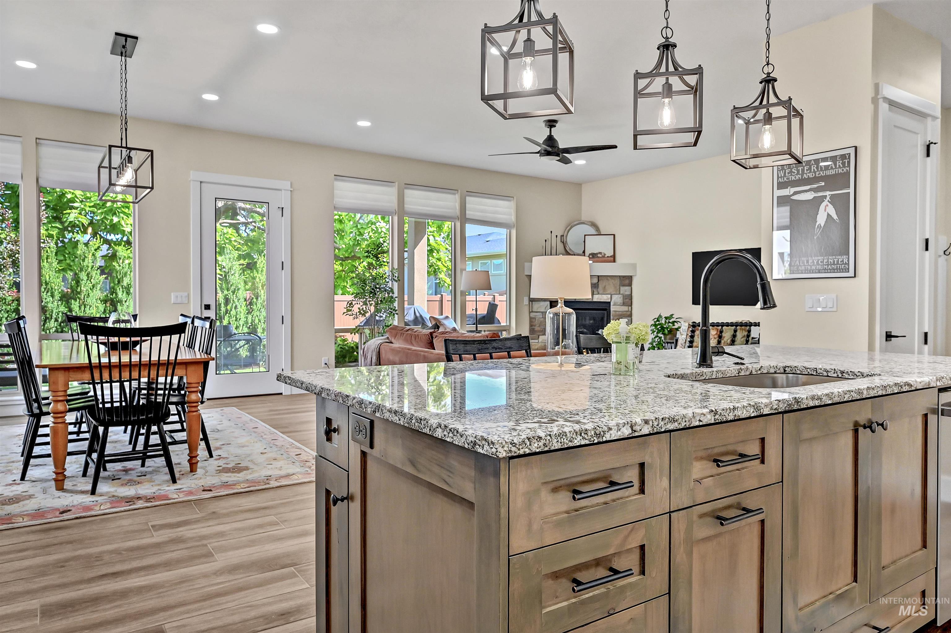 Kitchen with a ceiling fan, light wood-type flooring, recessed lighting, light stone countertops, and hanging light fixtures