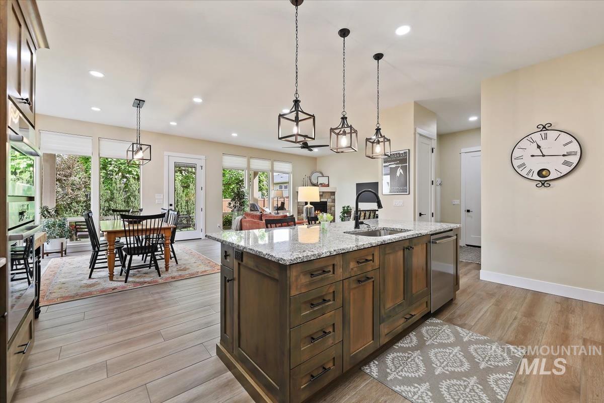 Kitchen featuring light stone countertops, decorative light fixtures, recessed lighting, a fireplace, and a center island with sink