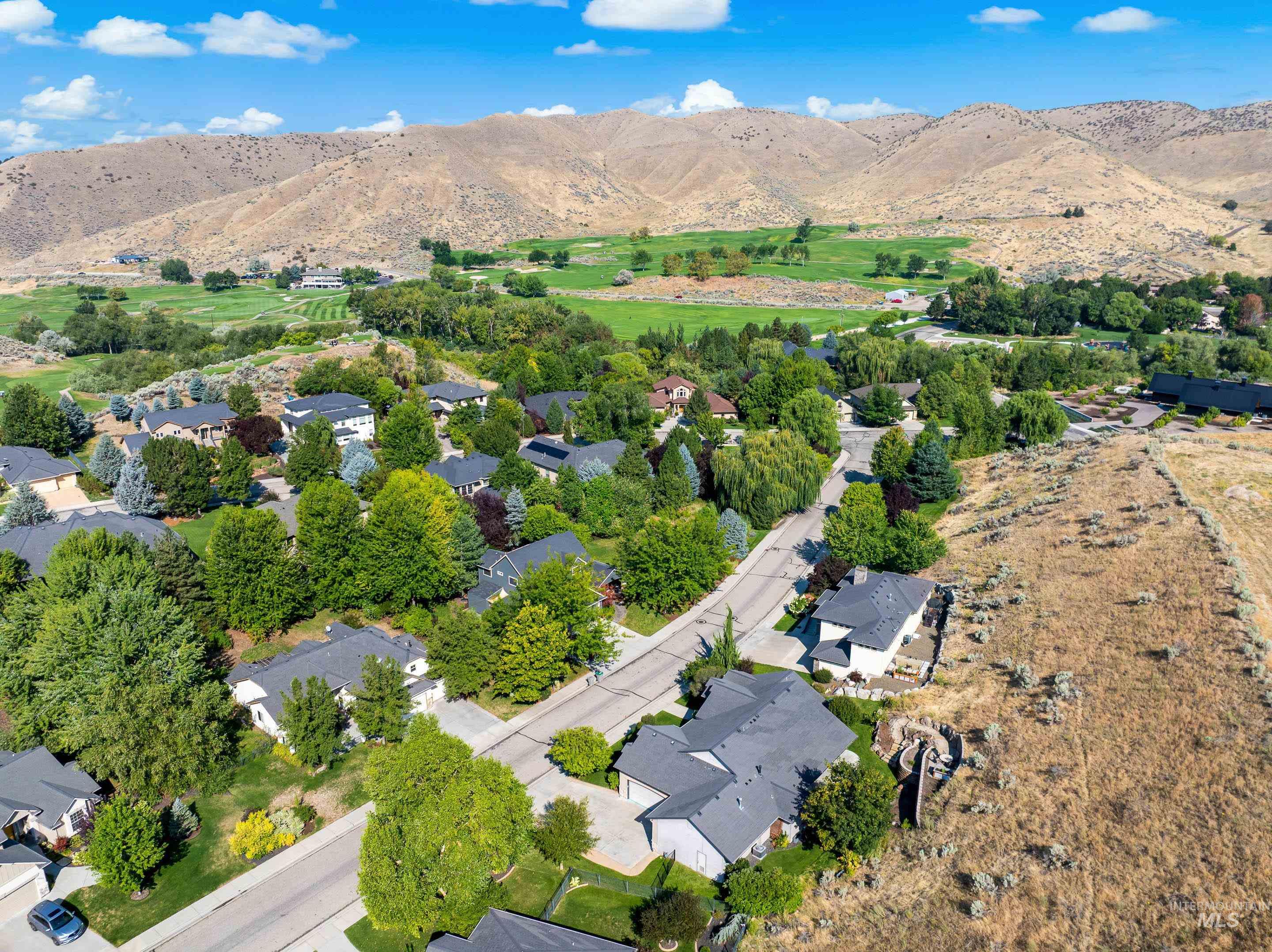 Aerial view of property and surrounding area with a mountain backdrop and nearby suburban area