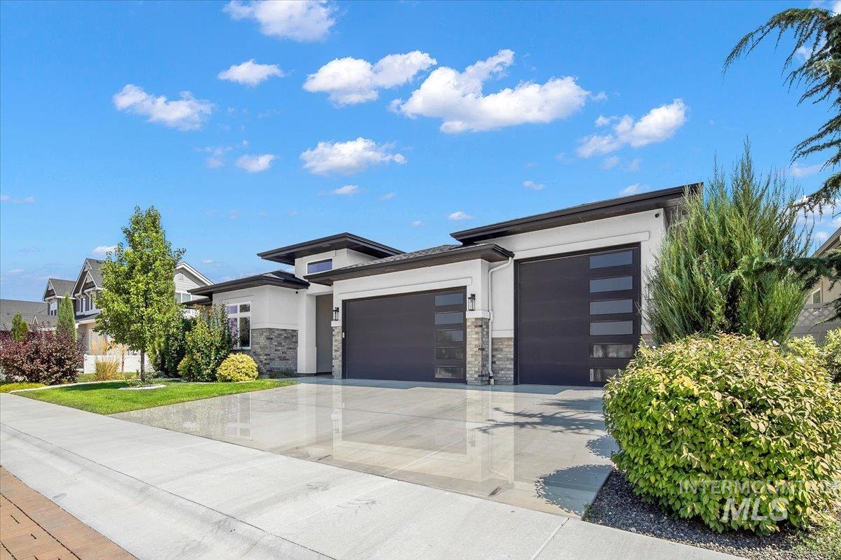 Prairie-style home featuring stucco siding, an attached garage, concrete driveway, and stone siding