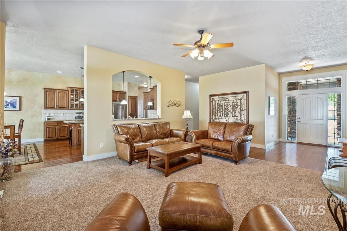 Living area featuring light wood finished floors, ceiling fan, light colored carpet, and a textured ceiling