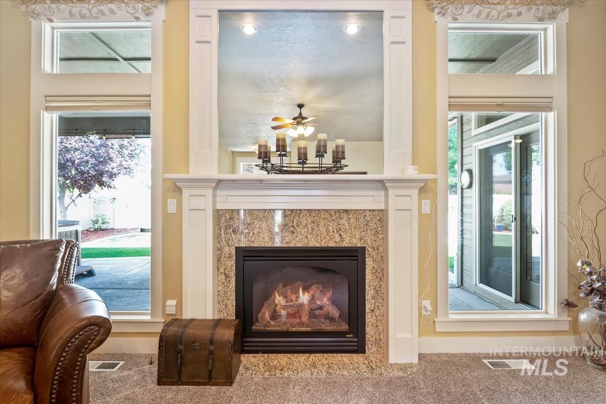 Detailed view of a fireplace, carpet floors, and a ceiling fan