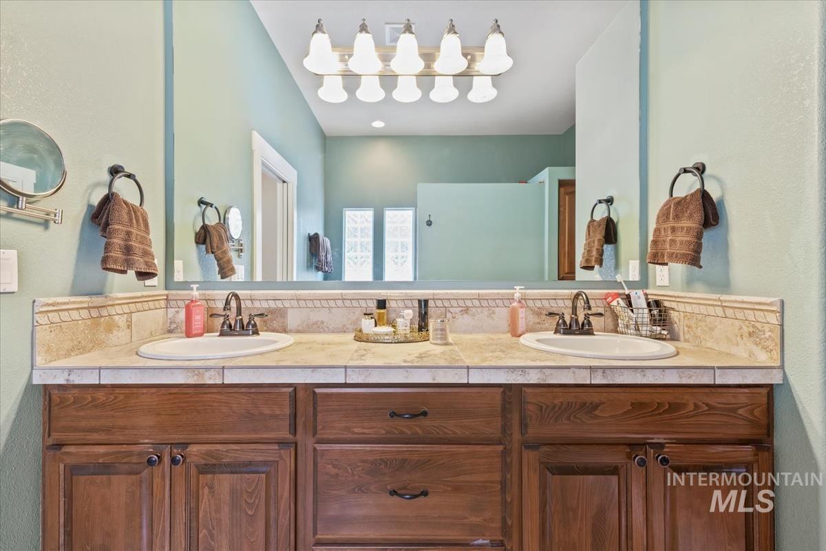 Bathroom featuring a textured wall and double vanity